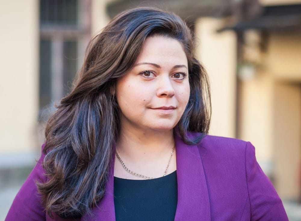 Woman with long brown hair and ain purple jacket